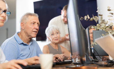 Curious mature man engaged in IT training during computer courses for adults