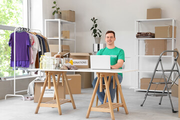 Male volunteer with food donations using laptop at table in center