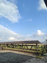 wooden fence on a farm, blue sky with clouds and a mountain in the distance