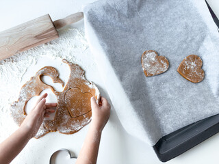 Child baking heart shaped cookies on a floured surface