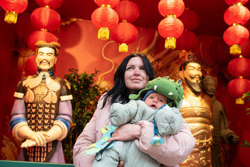 A woman holds her baby son in a dragon hat at the Chinese New Year festival in Moscow	