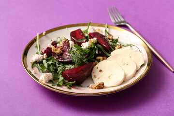 Plate of fresh salad with beet and mozzarella cheese on purple background