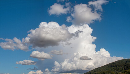 Fluffy white clouds floating in bright blue sky, nature's beauty