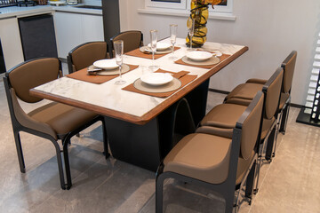 A modern dining set with a marble-patterned table and six brown leather chairs in a contemporary home
