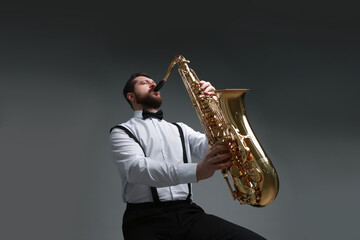 Fototapeta premium Professional musician playing saxophone on grey background, low angle view
