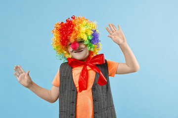 Happy boy dressed like clown on light blue background. Surprise party