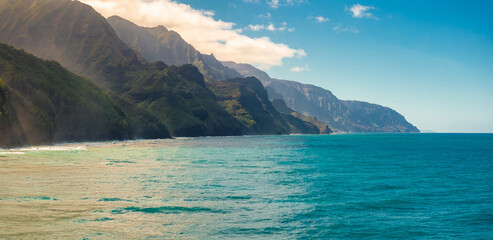 The Napali Coast on Kauai Island features rugged green cliffs descending into turquoise waters,...