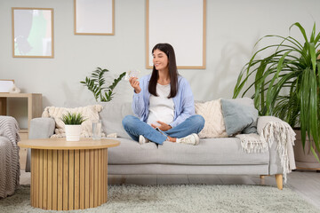 Young pregnant woman with vitamin B pills at home