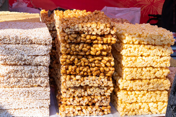 Stacks of traditional puffed rice or caramel treats are neatly arranged on a stall, showcasing a popular sweet snack.

