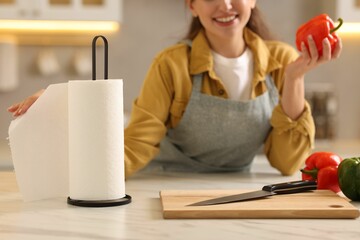 Woman with bell pepper using paper towels at white marble table in kitchen, closeup