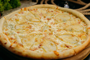 Gourmet pear and blue cheese pizza with pine nuts on wooden board in stylish restaurant setting