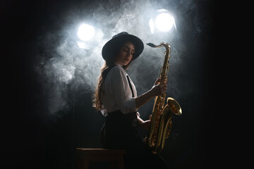 Professional musician playing saxophone on dark background with lights and smoke