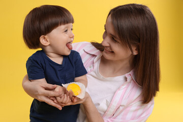 Mother and baby eating tasty mochi on yellow background