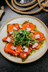 Roasted bell pepper carpaccio with arugula, feta cheese, pine nuts, and pesto, in gourmet style