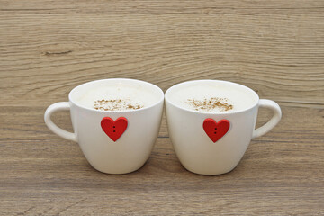 Two cappuccino cups decorated with red hearts for lovers