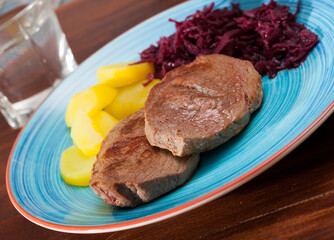 Veal Medallion de cadera with potato and sauerkraut..Healthy roasted beef steak served with baked potatoes and pickled cabbage..Grilled veal steak with boiled potato and marinated cabbage