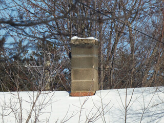 A brick chimney on a snowy roof