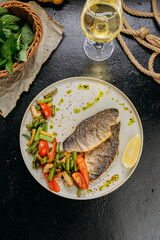 Grilled sea bream fillet with vegetables and lemon, plated with elegant garnish, fine dining style