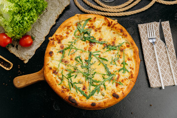 Gourmet four-cheese pizza with arugula, served on a wooden board in a stylish restaurant setting