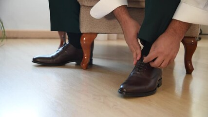 A gentleman putting on shoes. Elegant black shoes. Black men's shoes for the wedding day. Nice black shoes for the groom. Groom accessories for the wedding day