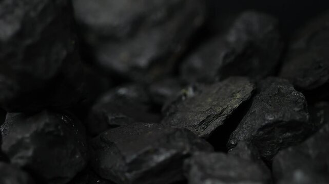 Coal chunks drop and collide in slow motion, breaking into smaller pieces. A macro study of this fossil fuel, beautifully lit for high-frame visuals.