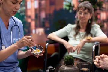 Medical assistant preparing daily dose of pills and vitamins for elderly patients, dividing the medicaments in separate bottles for effectiveness. Nurse giving medical drugs to people.