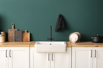 White ceramic sink and plates on wooden counter near dark blue wall in kitchen