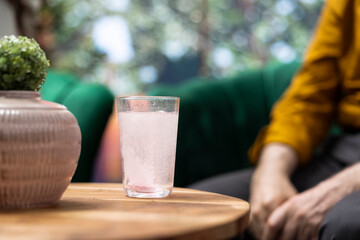 Senior man and woman serving their effervescent supplements with a glass of water, drinking the sparkling vitamins as part of their treatment. Elderly people at home during retirement. Close up.