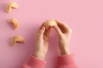 Female hands with fortune cookies on pink background