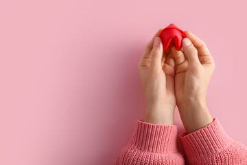 Female hands with red fortune cookie on pink background