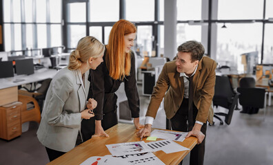 Two women and the boss are coworkers in the office.