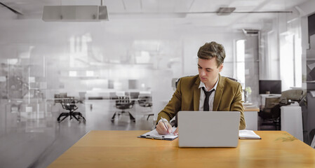 A young businessman in an office setting, using a laptop