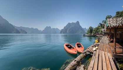 A canoe floats on the calm, blue waters of Khao Sok National Park, which is encircled by stunning mountains and a stunning sky Surat Thani of Thailand 