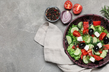 Bowl of tasty Greek salad, vegetables and peppercorns on grunge background