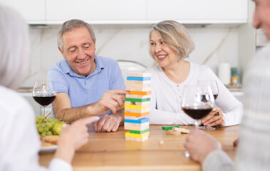 Elderly man and woman friends playing board game bricks at table