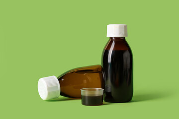 Bottles and measuring cup of cough syrup on green background