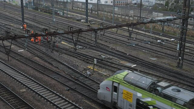 A train in motion and some railroad workers. Dijon, France - February 6, 2025. 
