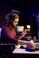 Audio engineer using stereo console to add sound effects on songs, working with daw software on pc...