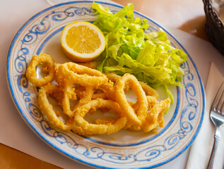 Fried calamari in a batter of tempera flour and fresh salad with lemon