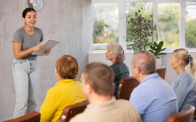 Fototapeta premium Young female professor giving lecture to elderly students