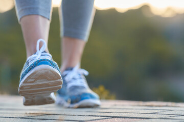 Woman walking on a pathway during sunset wearing athletic shoes for exercise and fitness