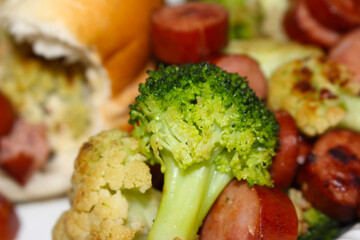 broccoli and cauliflower. broccoli with selective focus. food details. broccoli with sausage and bread blurred in the background.