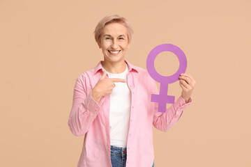 Beautiful mature happy woman pointing at gender symbol on beige background. Women history month