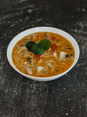 Soup in a white plate on a black background 