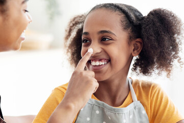Closeup portrait of black lady staining her smiling daughter nose with flour, cheerful...