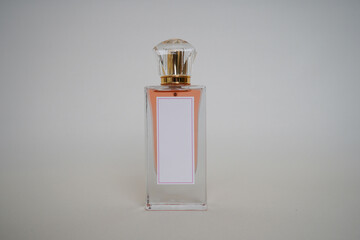 Close-up of a chic perfume bottle with a blank white label and golden cap, placed on a soft neutral...