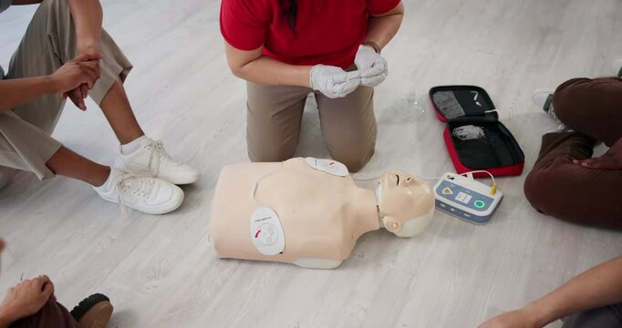 Paramedic, hands and talking with dummy for CPR class, first aid training or emergency healthcare practice on floor. Person, trainer or teaching with group for life saving lesson or rescue practical