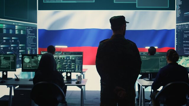 Military hacker from Russian army working in governmental control room cracking rival states network systems to spread fake news and hybrid war propaganda. Brainwashing ideology strategy. Camera B. - Powered by Adobe