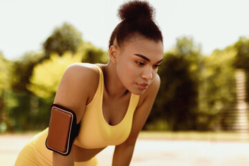 Urban Street Workout. Portrit of tired black young lady in yellow sportswear bra and arm band for...