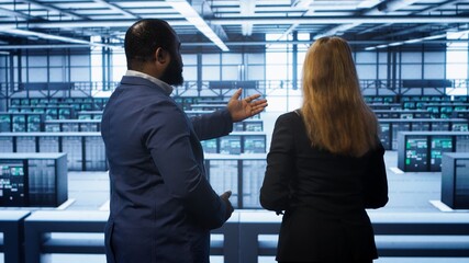 Data center engineer presenting equipment to inspector supervising operations. IT specialist in...
